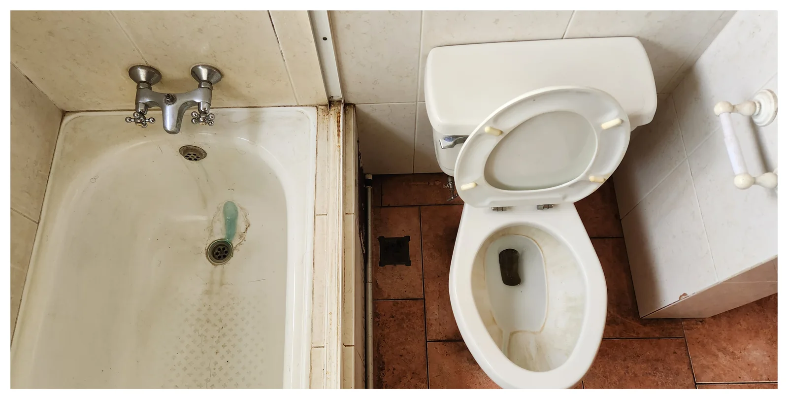 Baño con tina e inodoro y suciedad visible antes de la limpieza