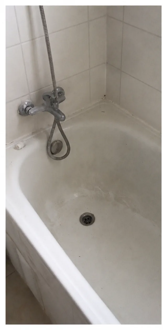 Tina y grifería de baño con manchas y suciedad visible