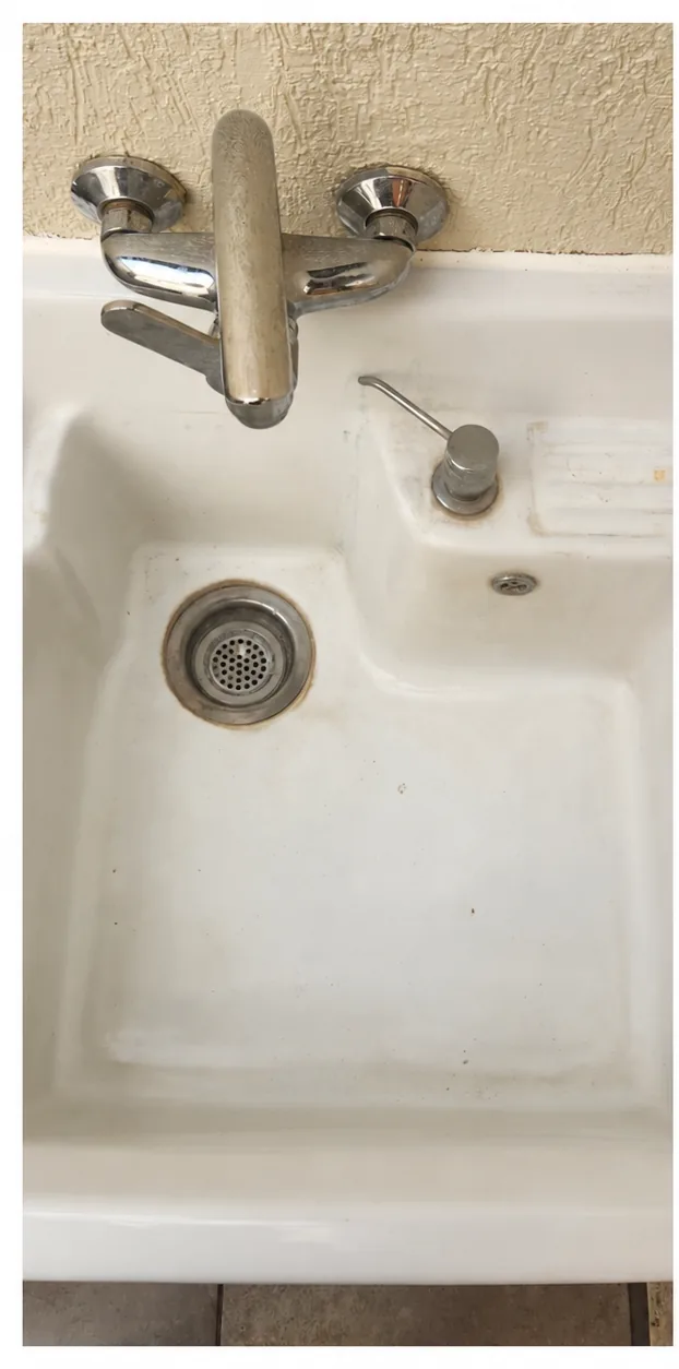 Lavadero blanco y grifería con manchas y suciedad