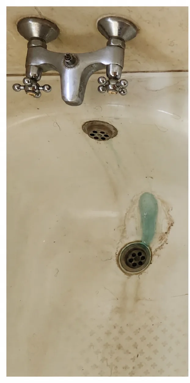 Tina blanca con sarro y manchas oscuras alrededor del desagüe