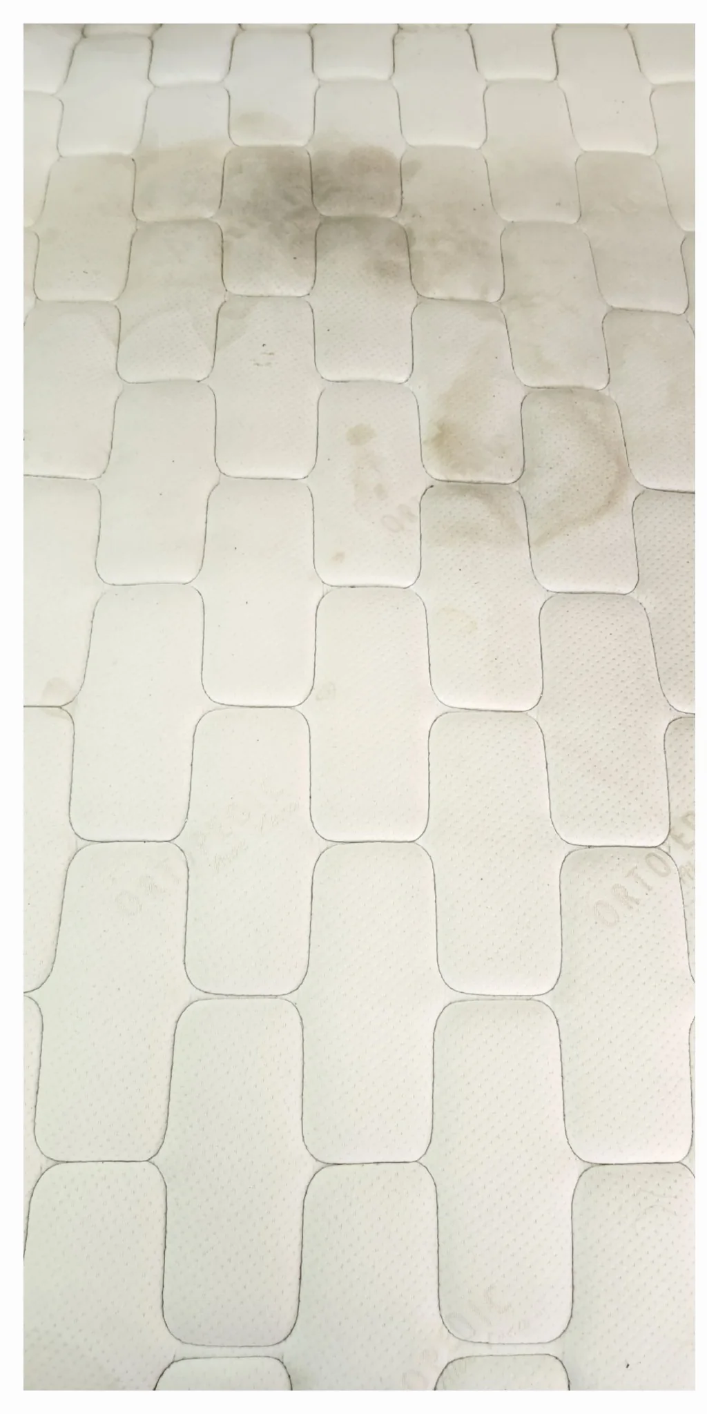 Colchón blanco de acolchado rectangular con manchas oscuras