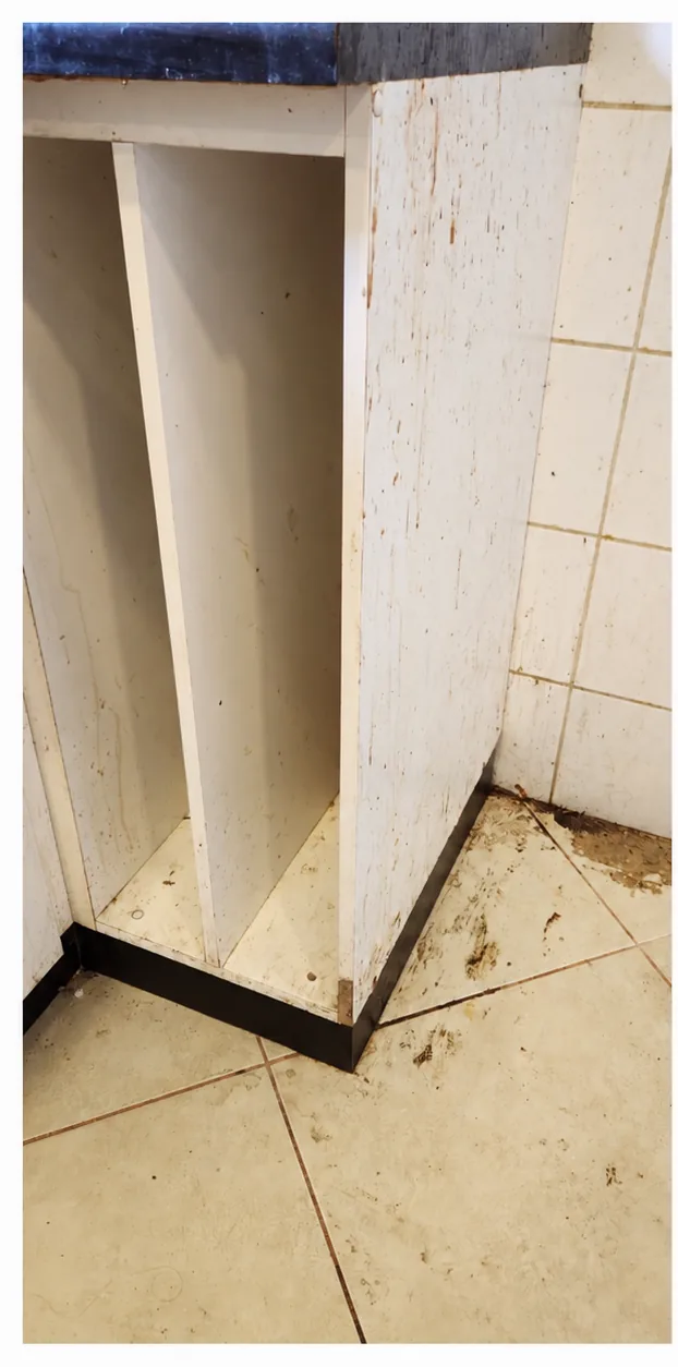 Mueble de cocina vacío con suciedad en los costados y el piso