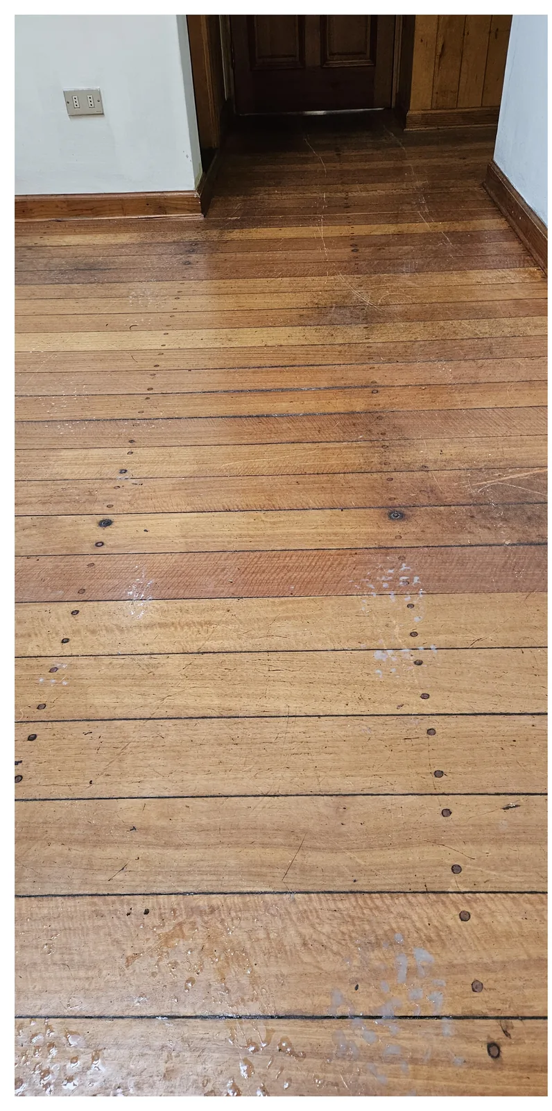 Tablas de piso de madera con marcas oscuras y acabado desigual