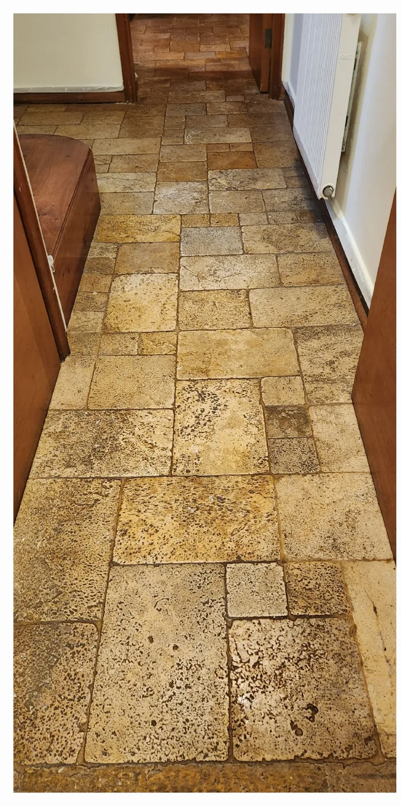 Piso de piedra con manchas oscuras y suciedad entre las piezas