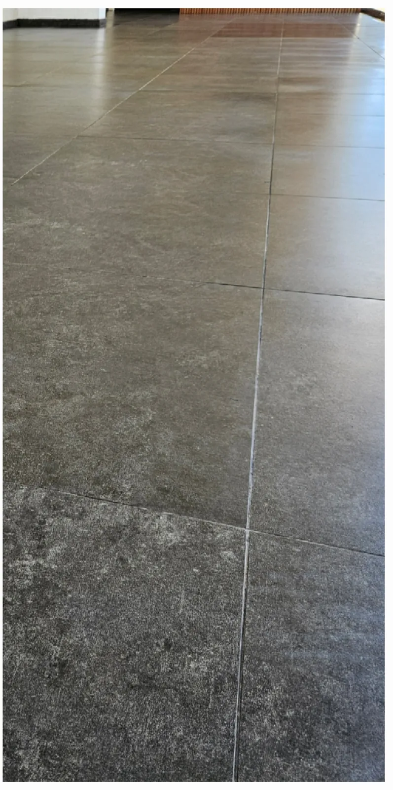 El mismo piso de baldosas grises después de retirar el polvo de obra