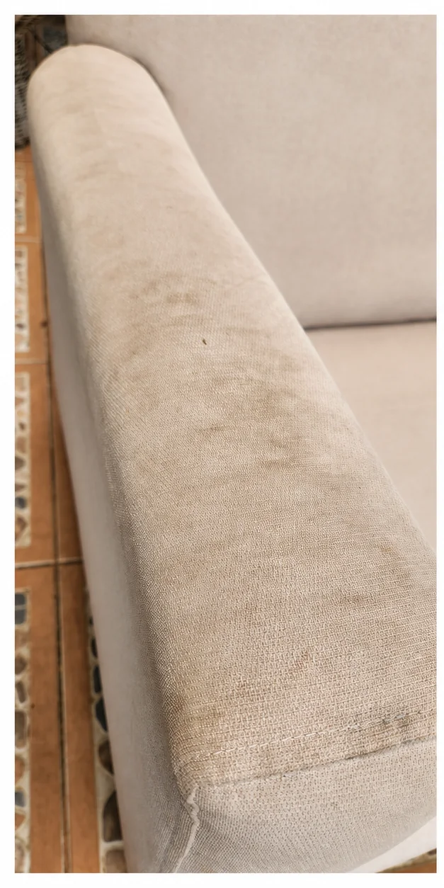 Brazo de sillón tapizado claro con manchas oscuras