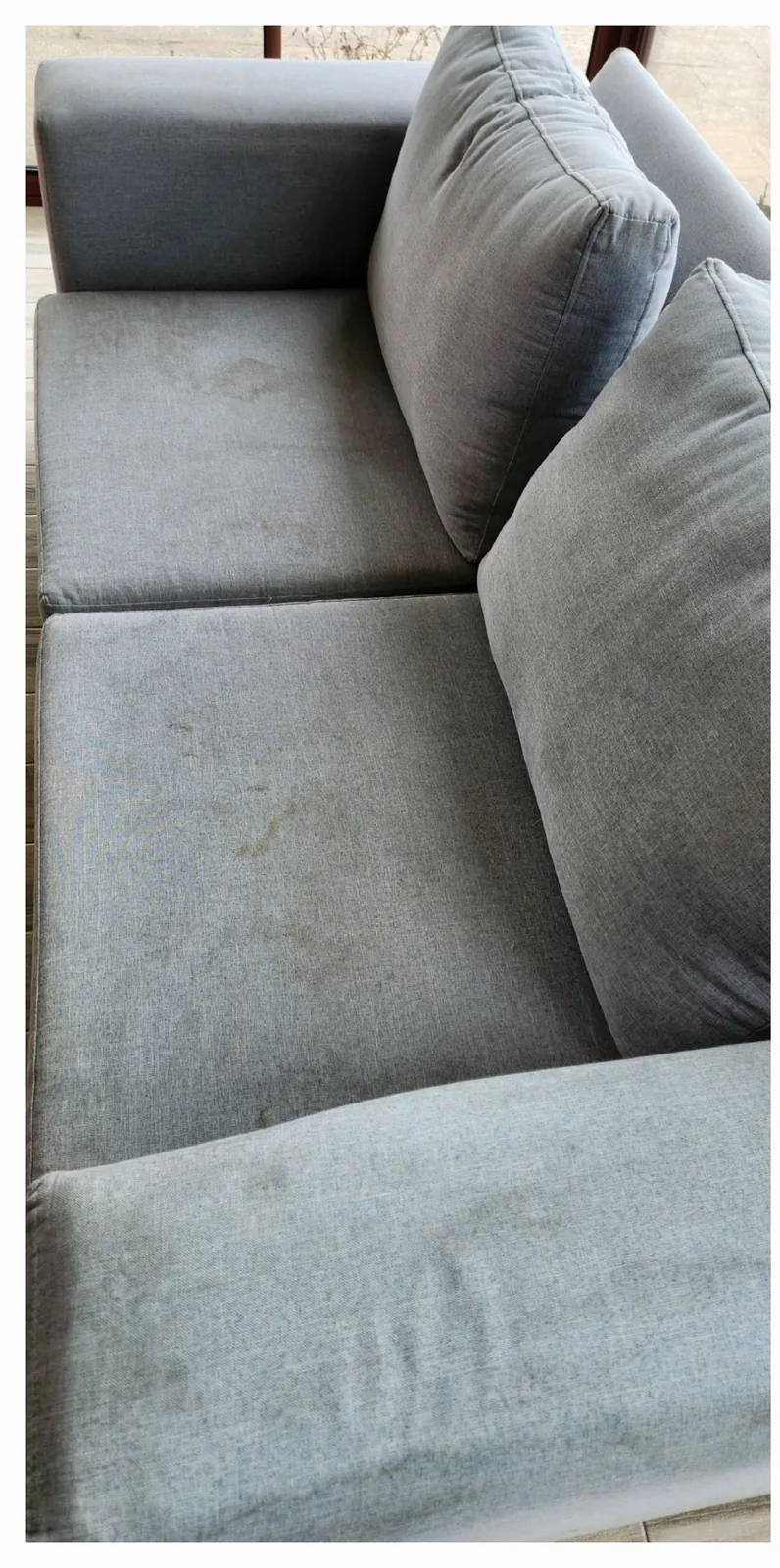 Asiento de sillón gris con marcas y zonas oscurecidas